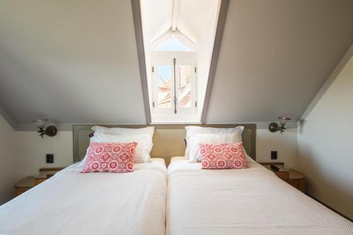 two beds with pink pillows in a room with a window at Chalet Saudade in Sintra