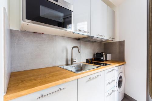 une cuisine blanche avec un évier et un micro-ondes dans l'établissement Spacious apartment - 3BR-6P - Champs Elysées, à Paris