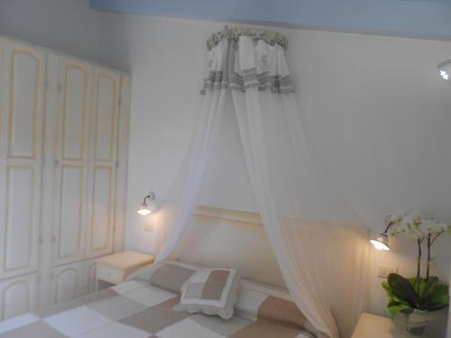 a white bedroom with a bed with a canopy at Hotel Tabby in Golfo Aranci