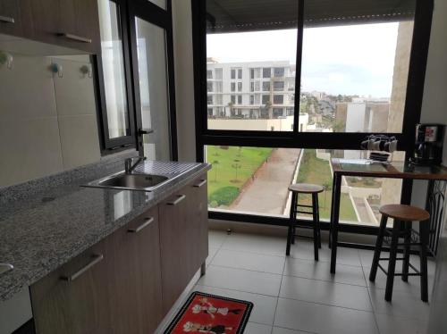 cocina con fregadero, mesa y ventana en Bel appartement à plage des Nation en Salé