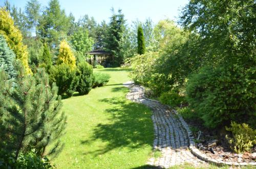 a garden with a creek and trees and a gazebo at Willa Maciejka in Trybsz