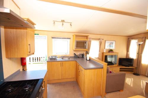a kitchen with wooden cabinets and a counter top at Caravan by Camber Sands 2 in Camber