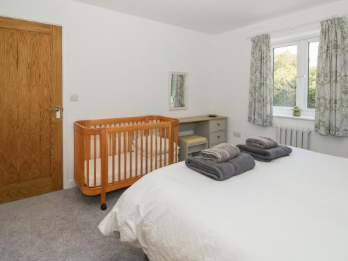 a bedroom with a crib and a desk with a window at The Glass House in Hunstanton