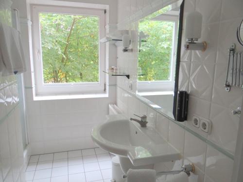 a white bathroom with a sink and a window at Landhaus Schulze-Hamann - Hotel garni - in Blunk