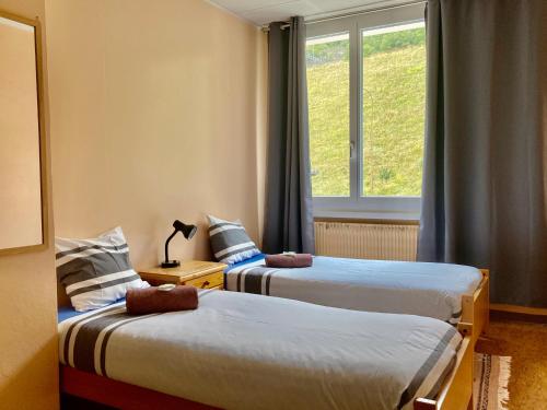 2 letti in una camera con finestra di Auberge Pour Tous a Vallorbe
