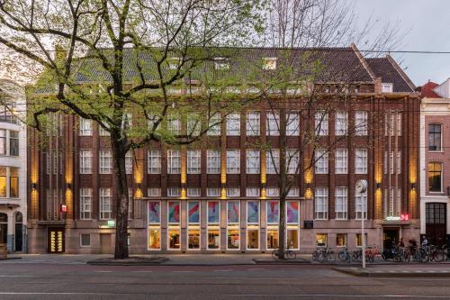 een groot bakstenen gebouw met bomen ervoor bij citizenM Amstel Amsterdam in Amsterdam