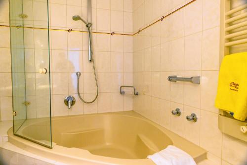 a bath tub in a bathroom with a shower at Hotel Almhof Rupp in Riezlern