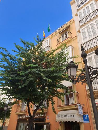 un edificio con un albero di fronte di Hostal Bahía a Cadice