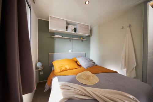 a bedroom with a bed with a hat on it at Camping le Village de Florine in Coëx