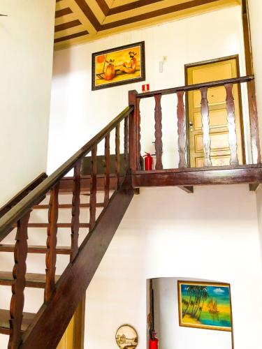 a wooden staircase in a house with paintings on the wall at Pousada Colonial Penedo - Alagoas in Penedo