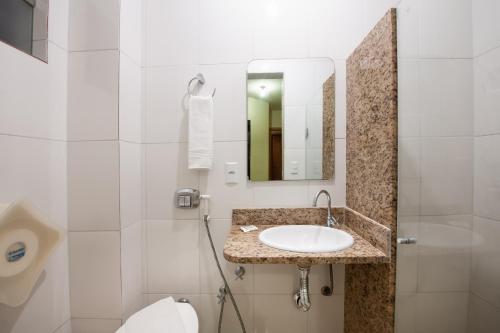 a bathroom with a sink and a toilet and a mirror at Hotel Pouso Alegre in Campo Grande