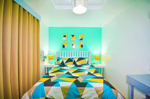 - une chambre avec un lit et une couette colorée dans l'établissement Charming Modern 2-Bedroom Apartment, Olongapo City Center, à Olongapo