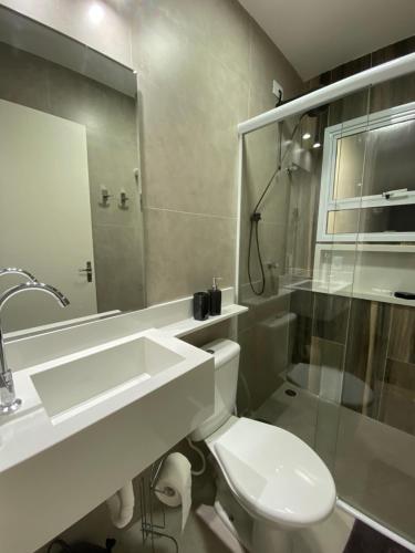 uma casa de banho branca com um lavatório e um WC em Apto Novo Duplex em Juqhey em Juqueí
