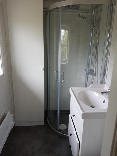 a white bathroom with a shower and a sink at Sjötorpet - unikt boende vid havet på norra Öland! in Löttorp