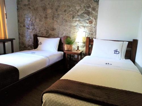 a hotel room with two beds and a stone wall at Ecohotel Bordones in Isnos