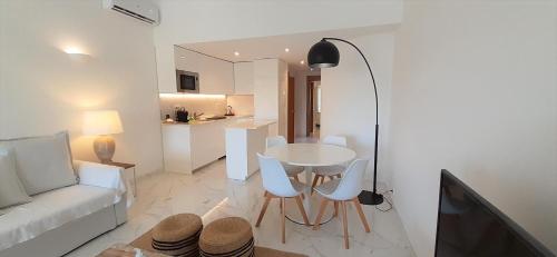 a living room with a white couch and a table and chairs at Quinta do Lago Beach House in Quinta do Lago