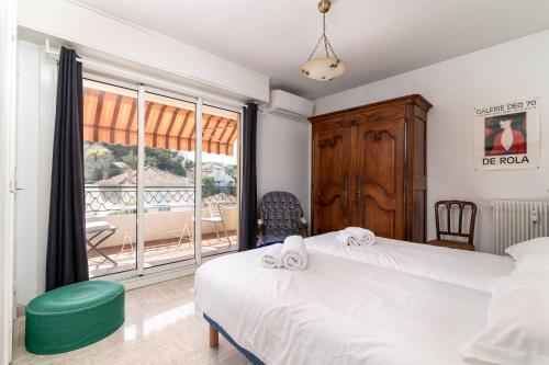 a bedroom with two beds and a large window at COPACABANA appartement 2 chambres in Cannes