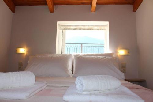 a bed with white pillows in a room with a window at New independent loft, 360⁰ view, 5' beach/center in Kalamata