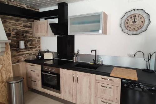 une cuisine avec un évier et une horloge murale dans l'établissement brelevenez 18 rue crec h quellien, à Lannion