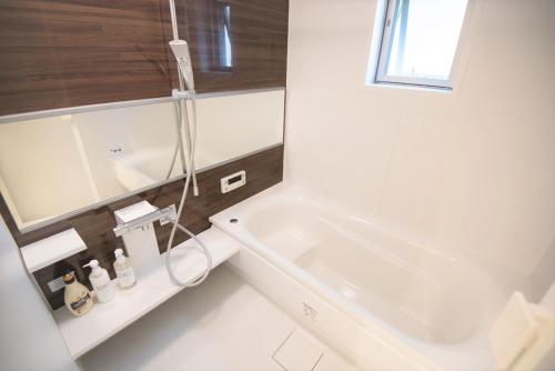 La salle de bains blanche est pourvue d'une baignoire et d'un lavabo. dans l'établissement Salon Shibuya - Vacation STAY 78187, à Tokyo