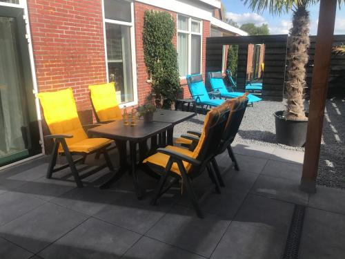 a patio with yellow chairs and a wooden table at Vakantie aan de Lauwers in Gerkesklooster
