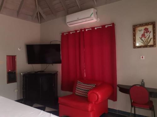 um quarto com uma cadeira vermelha e uma televisão em Jobs Inn Jamaica em Montego Bay