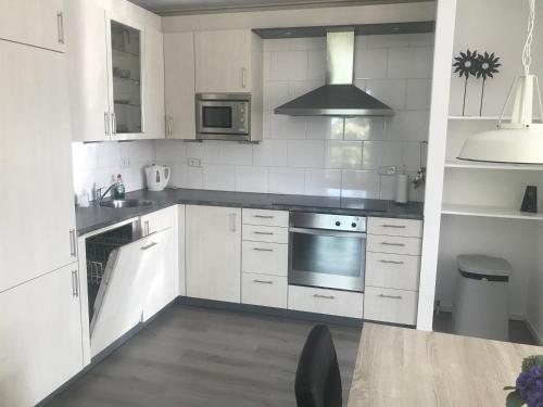 a kitchen with white cabinets and a stove top oven at Vakantie aan de Lauwers in Gerkesklooster