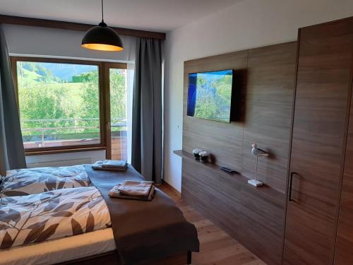 a bedroom with a bed and a large window at Exklusiv Apartment Sonnenalp in Niederau