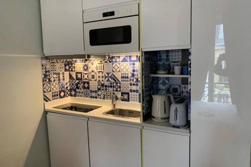 une cuisine avec des armoires blanches, un évier et un micro-ondes dans l'établissement PARIS 5 district LUXEMBOURG GARDENS, à Paris