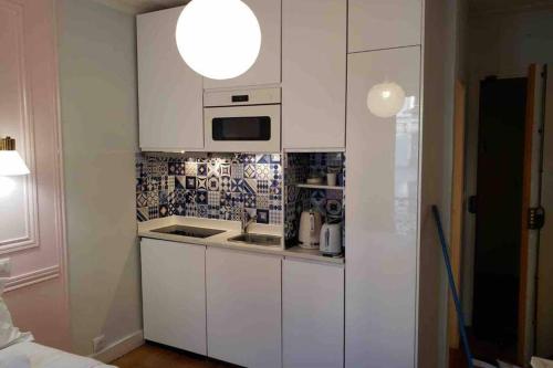 une petite cuisine avec des armoires blanches et un évier dans l'établissement PARIS 5 district LUXEMBOURG GARDENS, à Paris