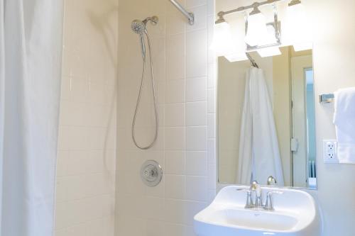 a white bathroom with a shower and a sink at The Plaza Hotel - Milwaukee in Milwaukee