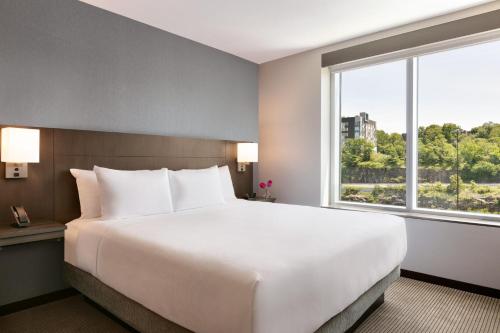 a large bed in a hotel room with a large window at Hyatt Place Fort Lee/George Washington Bridge in Fort Lee