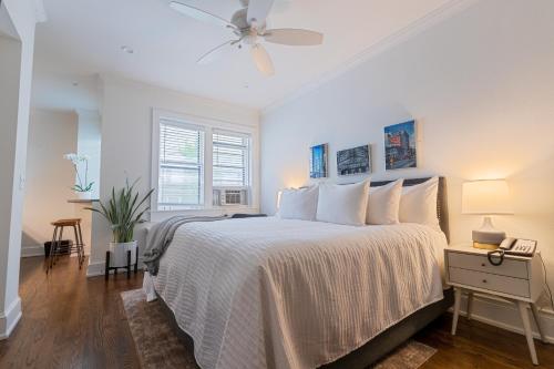a white bedroom with a bed and a ceiling fan at The Plaza Hotel - Milwaukee in Milwaukee