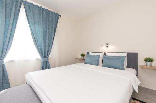 a bedroom with a large white bed with blue curtains at Apartman Mares in Krk