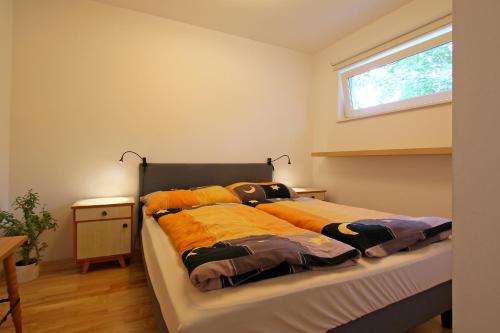 Bett in einem Zimmer mit Fenster in der Unterkunft Am sonnigen Waldrand in Innsbruck