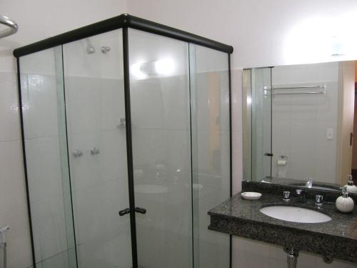 
a bathroom with a shower, sink, and mirror at Pousada Omnimare in Ubatuba
