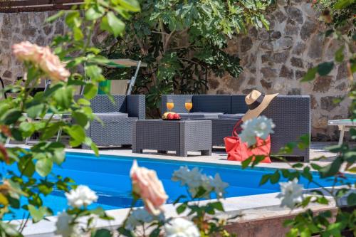 a person in a hat sitting on a chair next to a pool at Apartments My Przno in Sveti Stefan