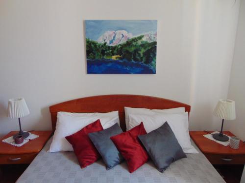 - un lit avec quatre oreillers et un tableau mural dans l'établissement Apartments Petra, à Biograd na Moru