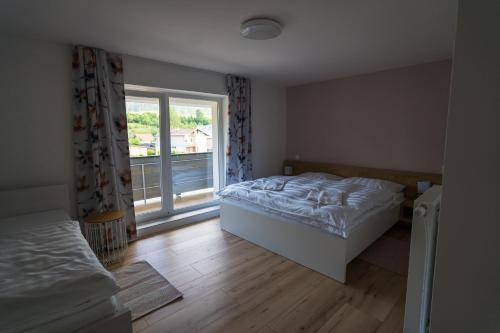 a bedroom with a bed and a large window at Apartmány EMA a PETER in Terchová