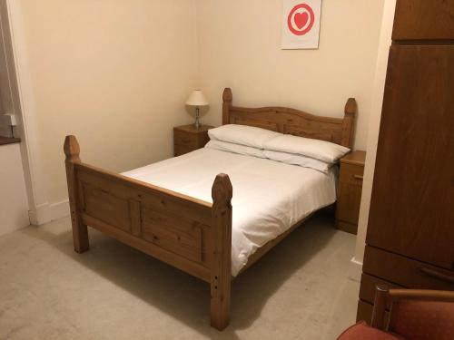 a bedroom with a wooden bed with white sheets at Spacious comfortable flat in Scalloway, Shetland. in Scalloway