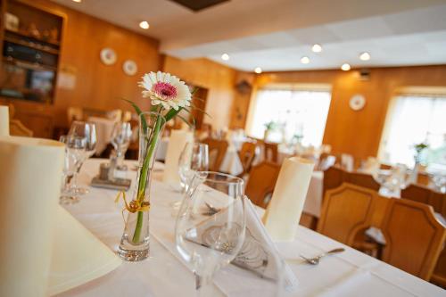 a dining room with a table with a vase with a flower at Tannmühle Hotel und Restaurant GmbH in Callenberg