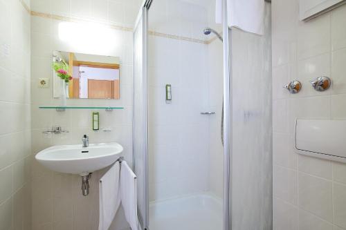 a white bathroom with a sink and a shower at Tannmühle Hotel und Restaurant GmbH in Callenberg