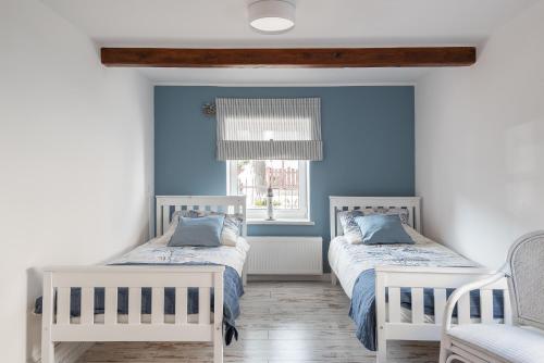 two beds in a room with blue walls at PATYKIEM PO WODZIE in Jastarnia