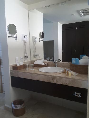 a bathroom with a sink and a large mirror at Akumal Bay Beach & Wellness Resort in Akumal