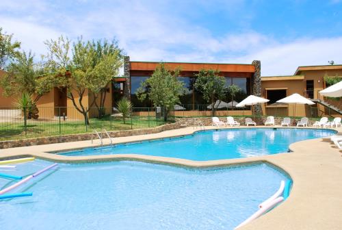 a large swimming pool with chairs and a building at Olmue Natura Lodge & Spa in Olmué