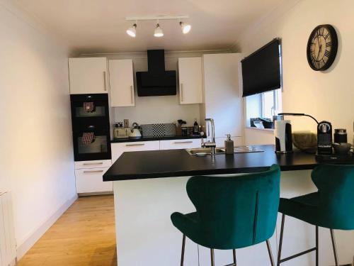 a kitchen with a counter and two green chairs at Sonas Luxury Living in Dungarvan