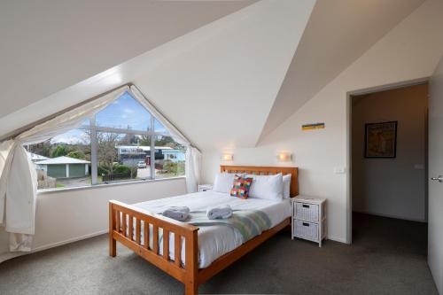 um quarto com uma cama e uma grande janela em A Hop, Skip & Jump to The Lake em Taupo