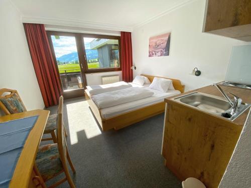 ein Schlafzimmer mit einem Bett und einem Waschbecken sowie eine Küche in der Unterkunft Pension Franglhof in Kirchberg in Tirol