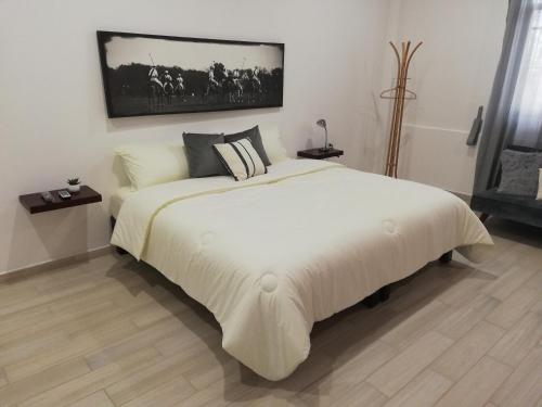 1 dormitorio con 1 cama blanca grande con una foto en la pared en La Maja Suites en Villahermosa