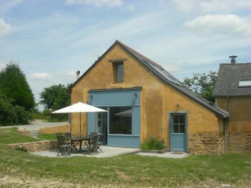 una casa con mesa y sombrilla en Chambres d'hôtes La Penhatière, en Baulon